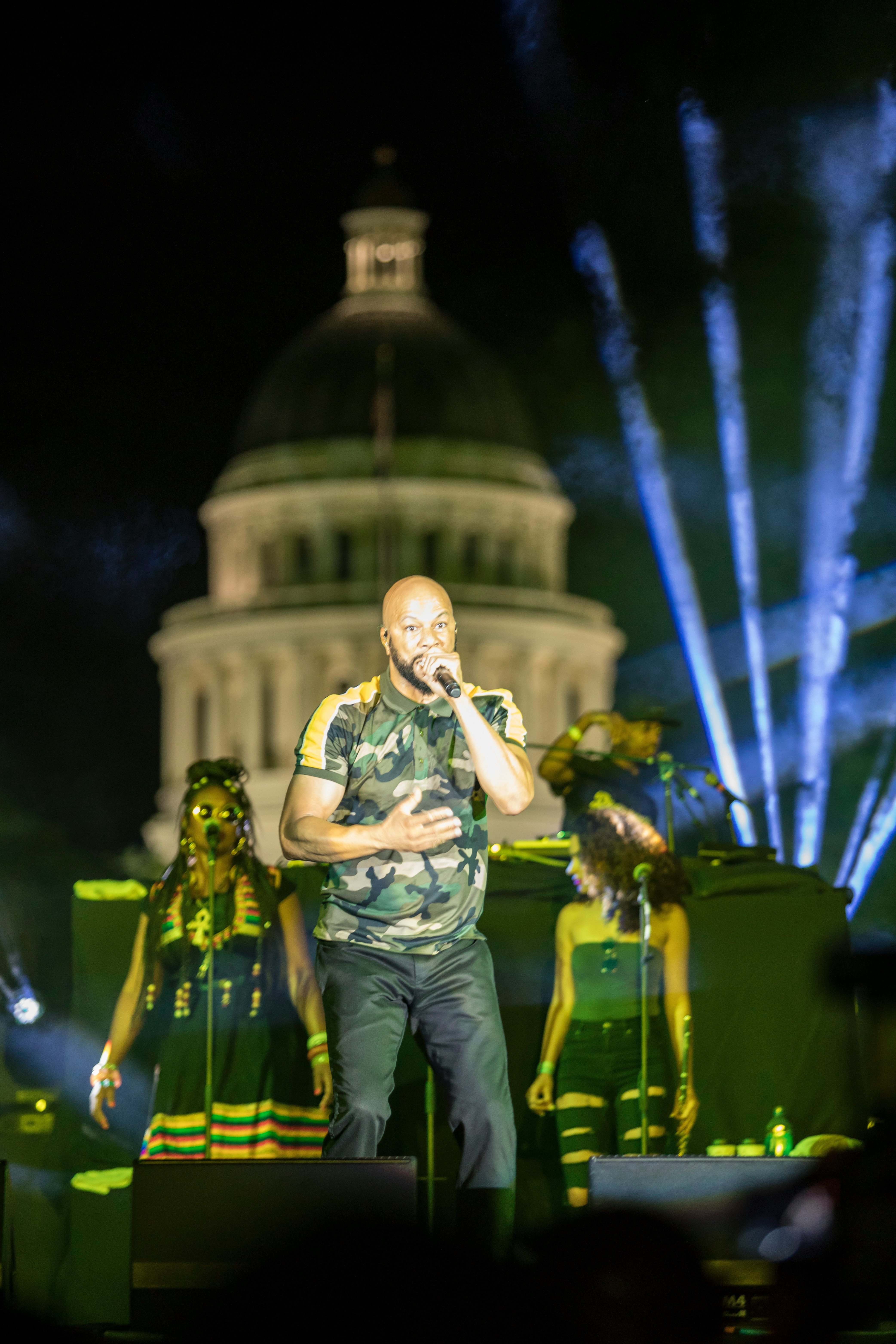 man in green shirt and blue denim jeans singing on stage